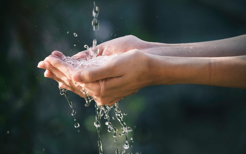 closeup water flow to hand of women for nature concept on the garden background.
